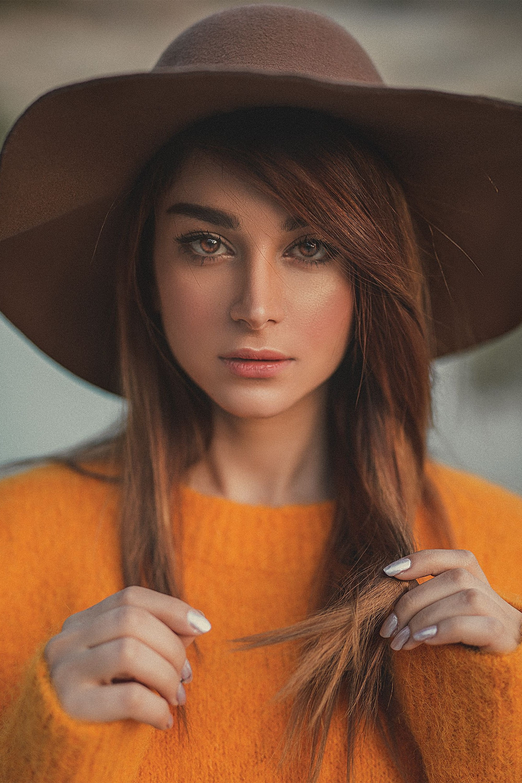 A woman in an orange sweater and wide hat