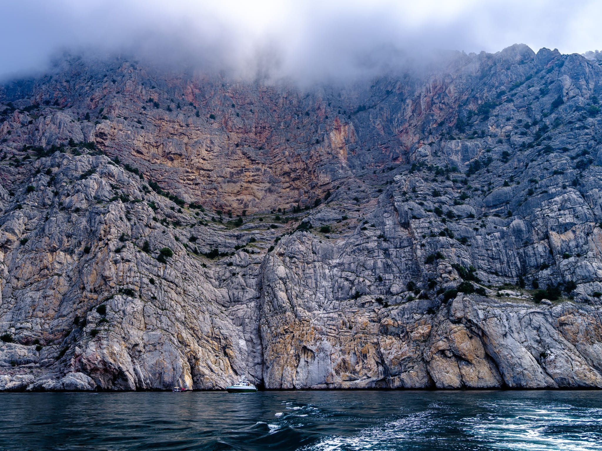 A cliff face rising into fog